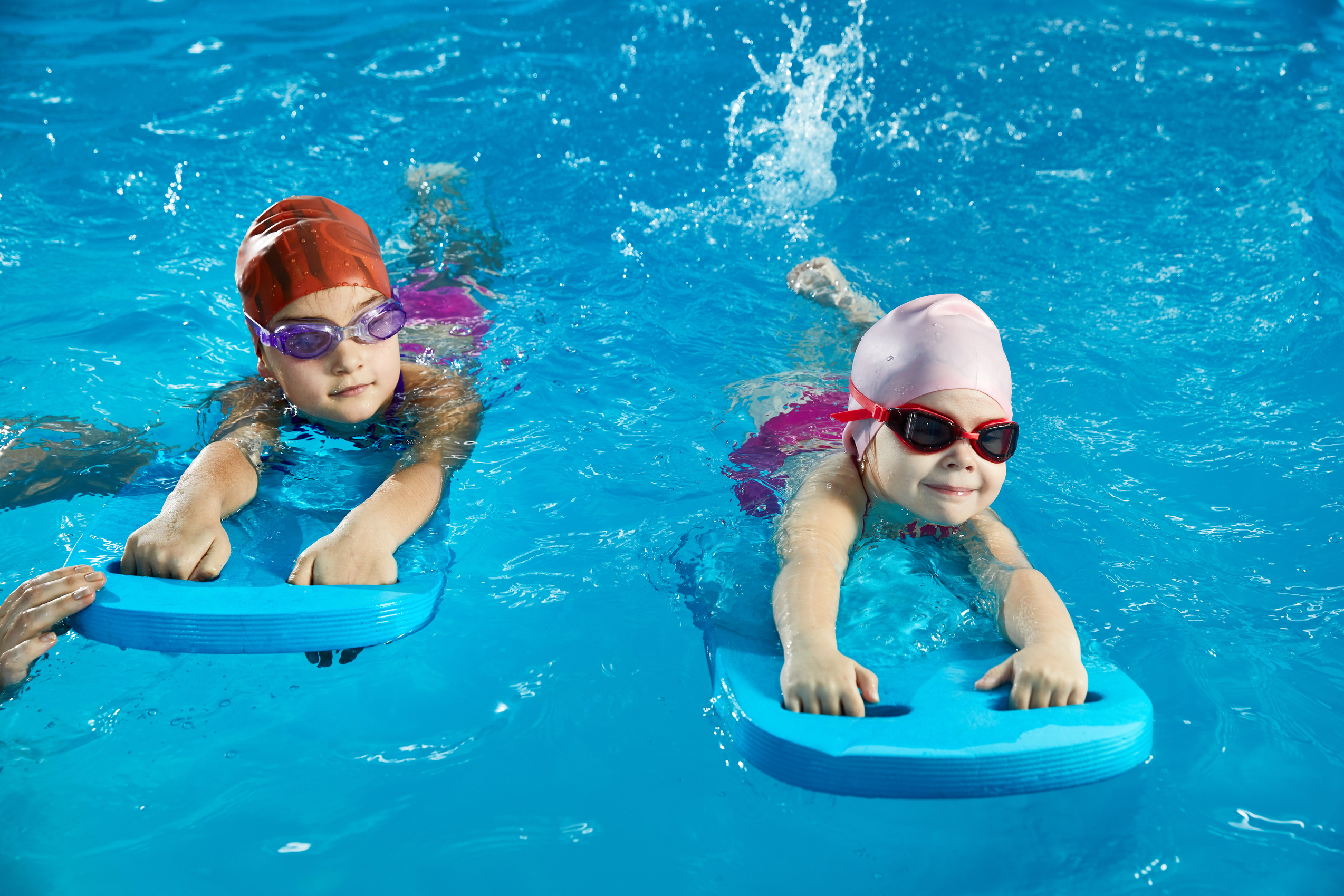 Two little girls learning swim indoor pool with pool board
